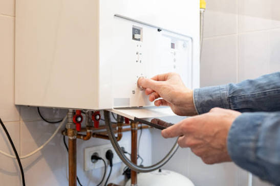 Hands adjusting the pressure controls beneath a domestic combi boiler
