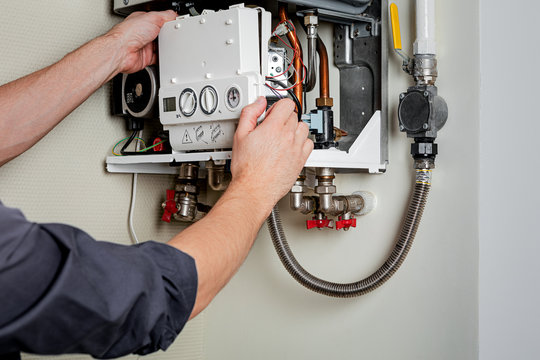 Heating engineer working on the internal components of an open boiler