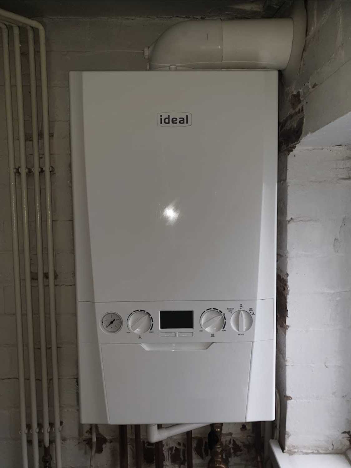 Ideal combi boiler mounted on a brick wall showing its display and controls