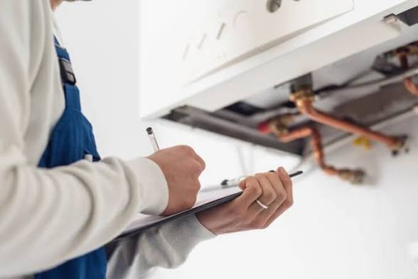 Gas Safe engineer recording boiler service checks on a clipboard